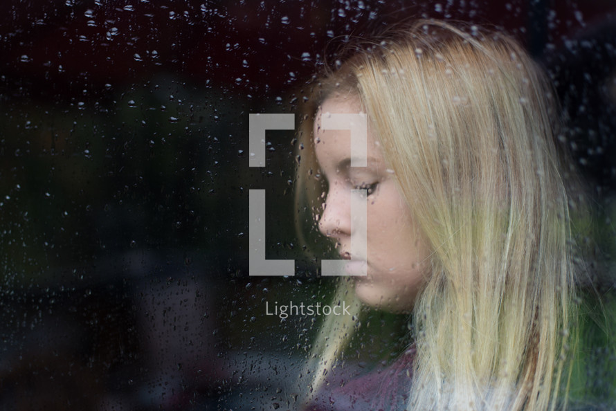 side profile of a woman through a rainy window 