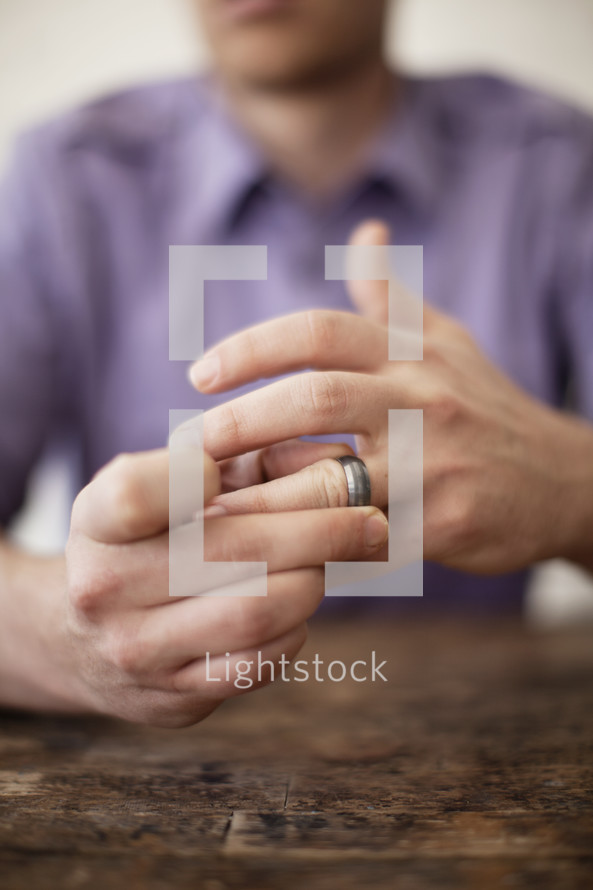 A married man removing his wedding band from his finger.