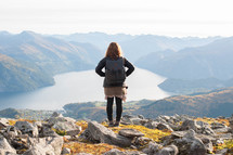 a woman looking out at a lake in a mountain valley 