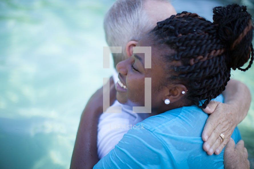 Man and woman hugging after a baptism in a pool of water.