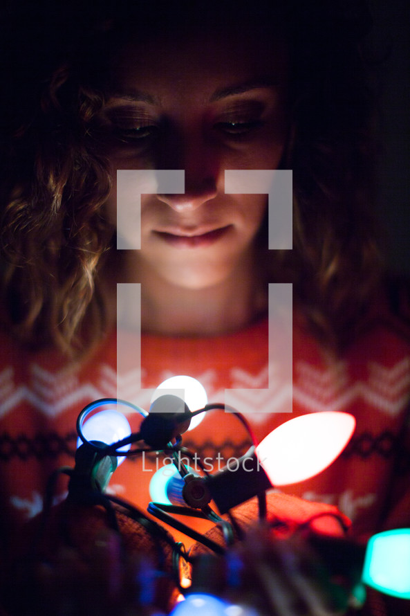 woman holding a string of glowing Christmas lights 