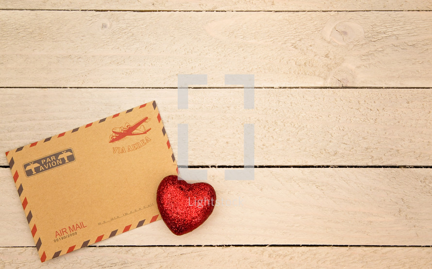 envelope and red heart on wood 