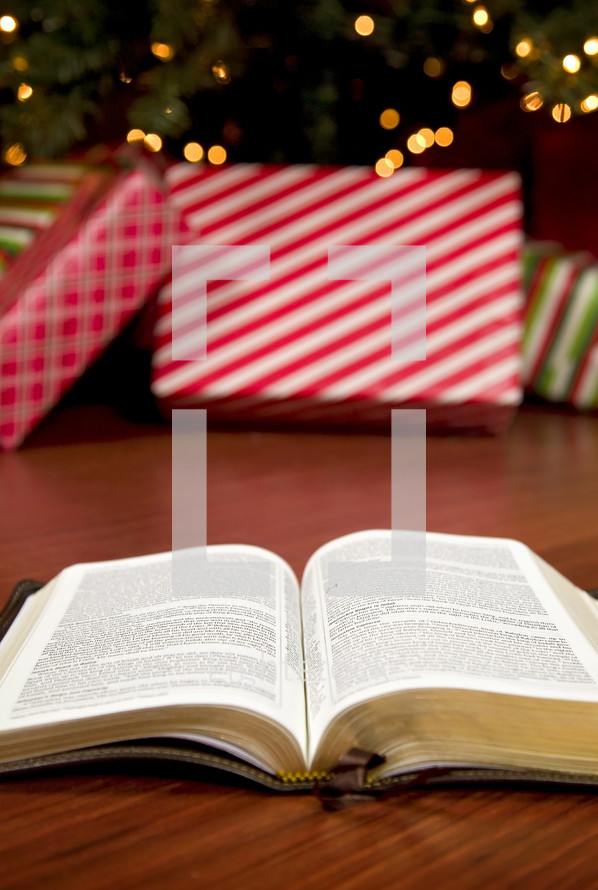 open Bible on the floor in front of a decorated Christmas tree 