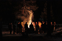 Silhouette of people around a bonfire at night.