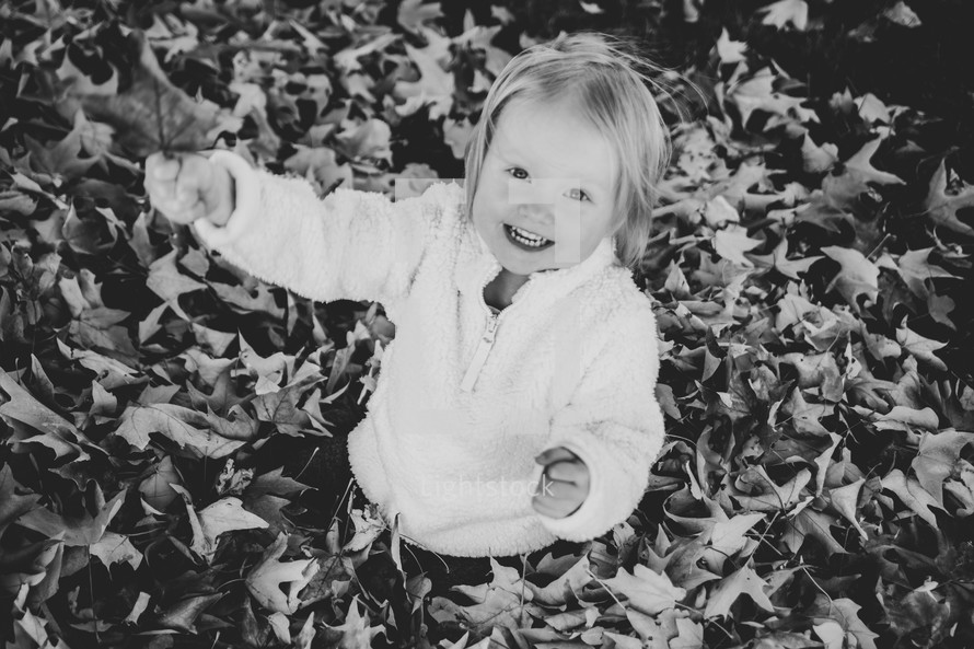 a little girl playing in fall leaves 