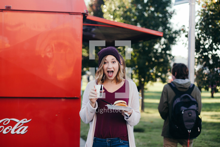 a woman getting food and drink from a food truck 