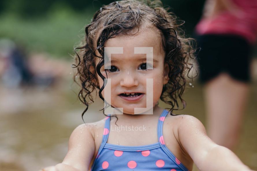 a toddler girl in a bathing suit with wet hair 