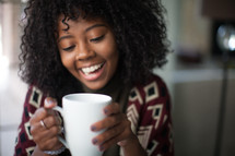 a woman holding a coffee mug smiling 