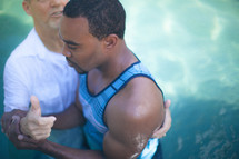 Man baptizing a man n a pool of water.