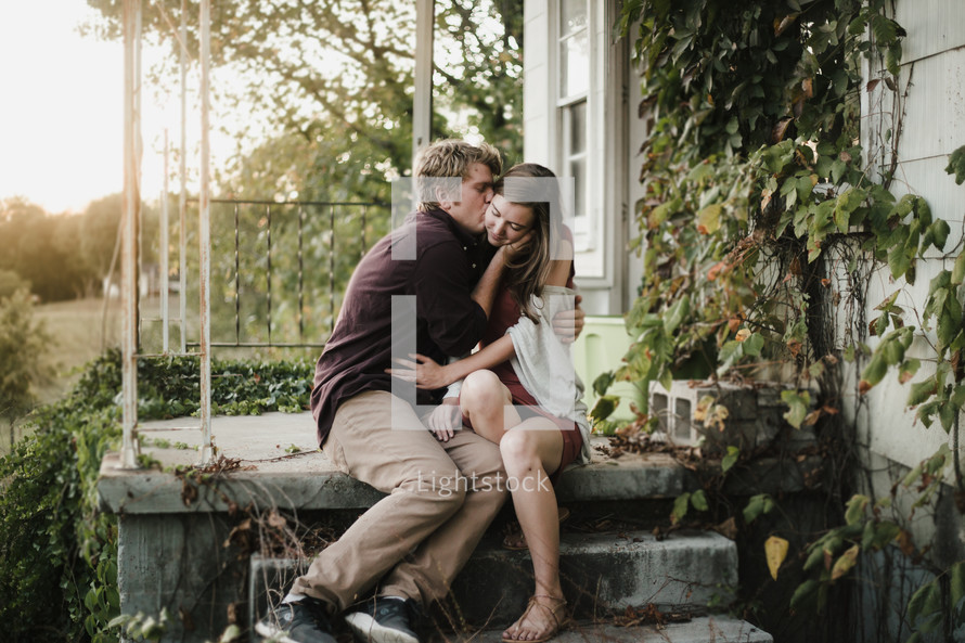 man kissing a woman on a porch
