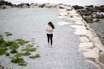 woman walking on a rocky beach 