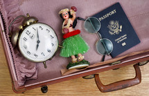 alram clock, passport, Hawaiian dancer, and glasses in a suitcase 