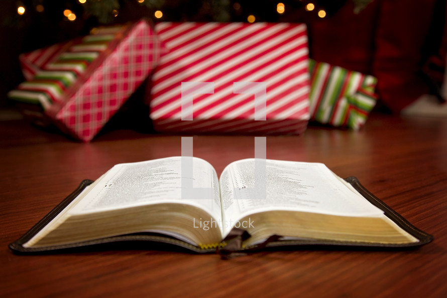 an open Bible on the floor in front of a decorated Christmas tree 