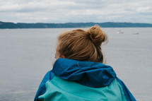 a teen girl looking out at lake water 