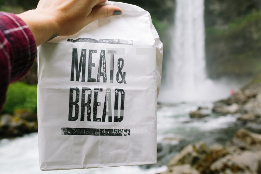 meat and bread paper sack near a waterfall 
