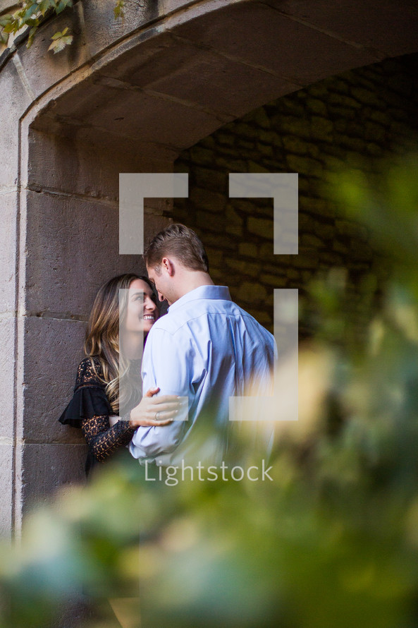 a couple kissing under an archway in a garden 