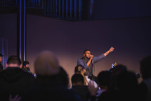 man singing into a microphone at a worship service