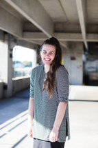 a smiling young woman standing in a parking garage 