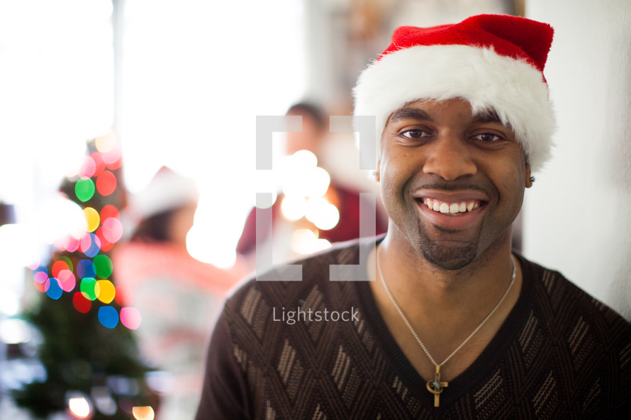 A man in a santa hat smiling at a Christmas party