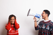 man in an ugly Christmas sweater yelling into a megaphone
