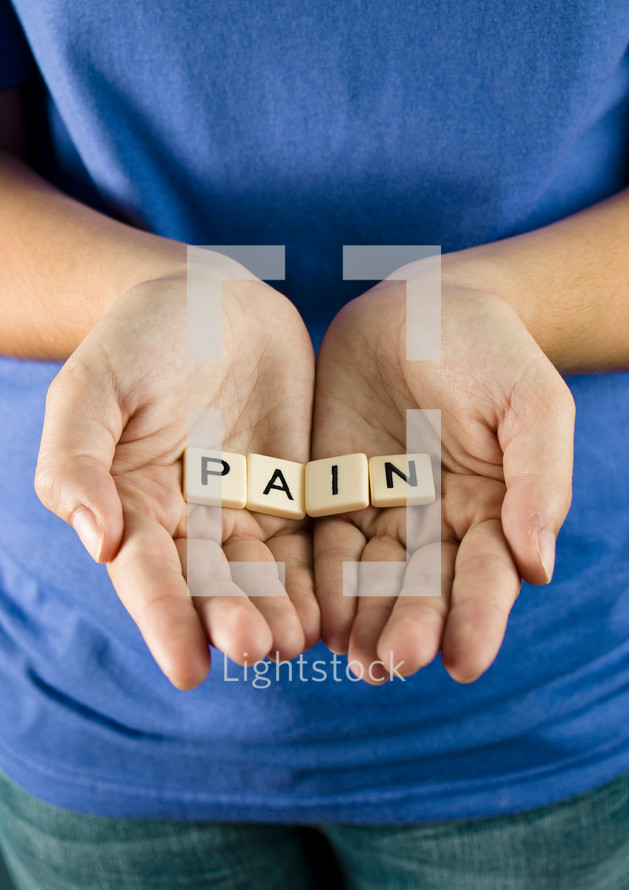 A young girl holds out the word "PAIN"