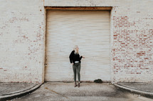 woman standing in front of a garage door posing 