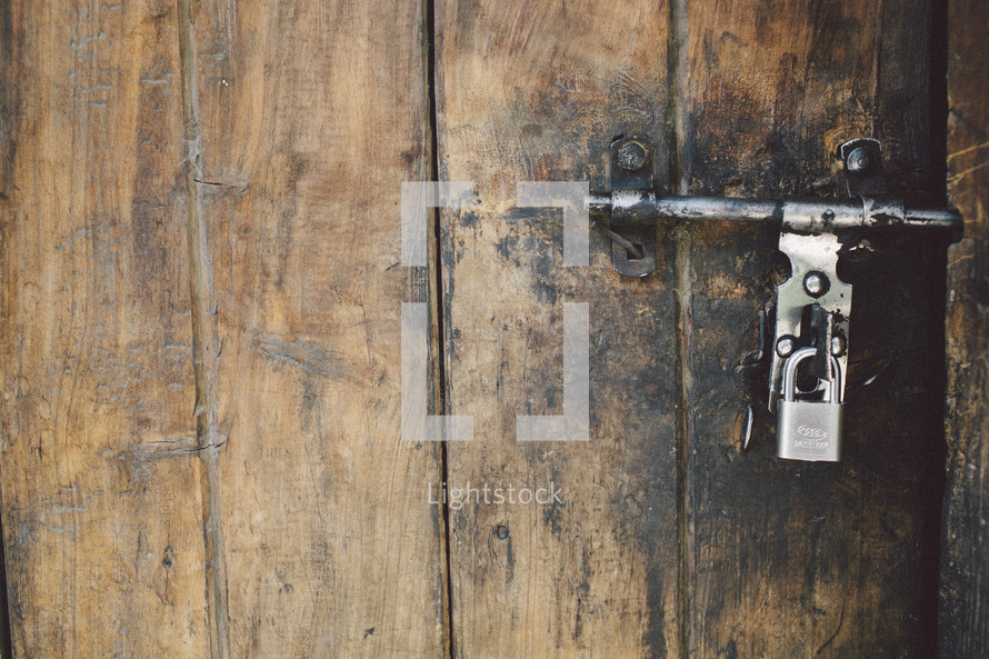 A padlock on an aged wooden door.