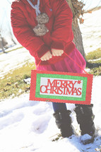a woman holding a Merry Christmas sign 