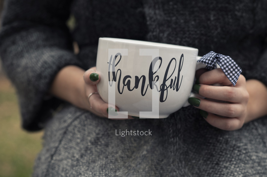 a woman holding a Thankful mug 