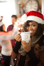 A young woman wearing a santa hat and holding a cup of coffee