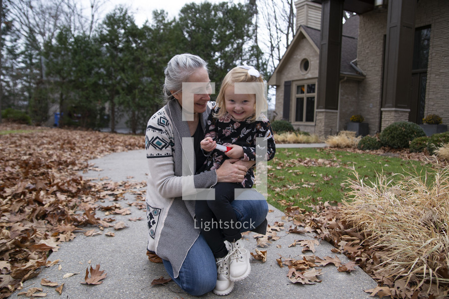 Child and grandmother on sidewalk in the fall