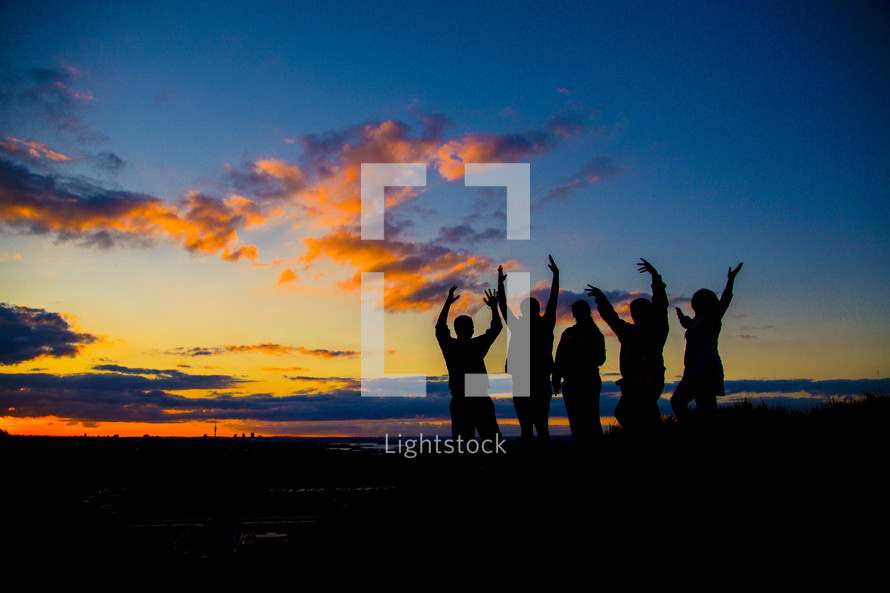 silhouettes of people with raised hands 