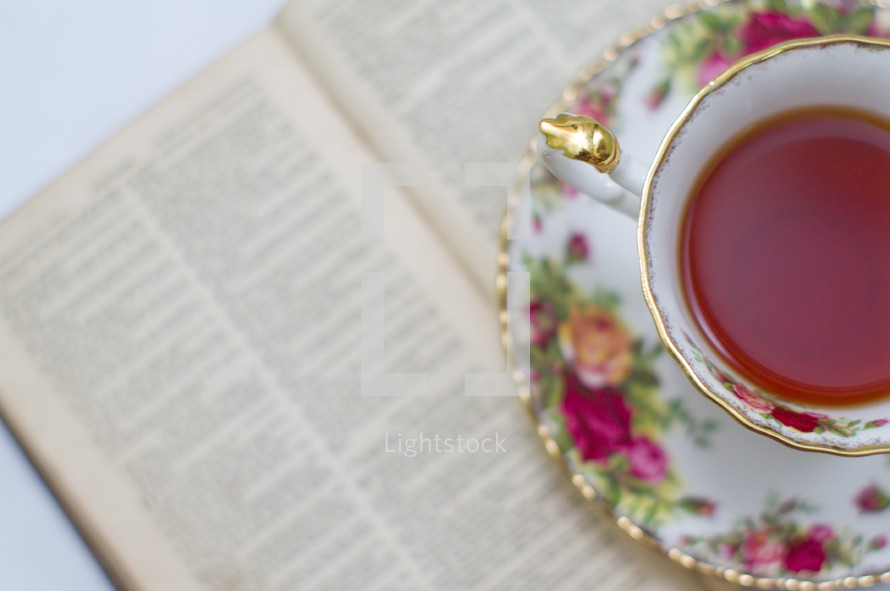 tea in a tea cup and an open book 