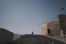 man walking up steps to a fortress 