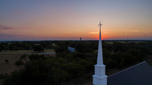 Traditional church steeple in the countryside at sunset.