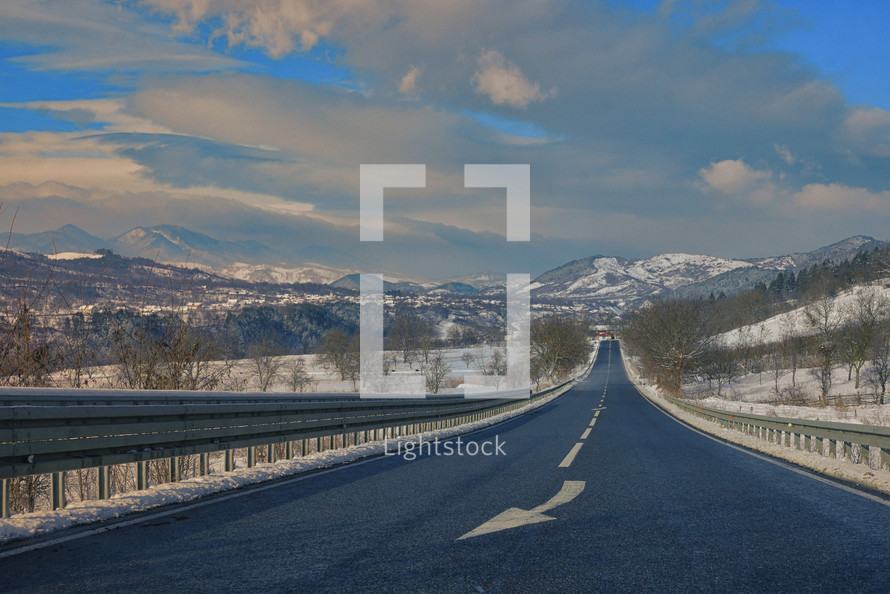 Classic winter scene of a road and mountains in rural area