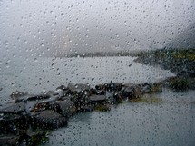 rain drops on a window with view of a shore 
