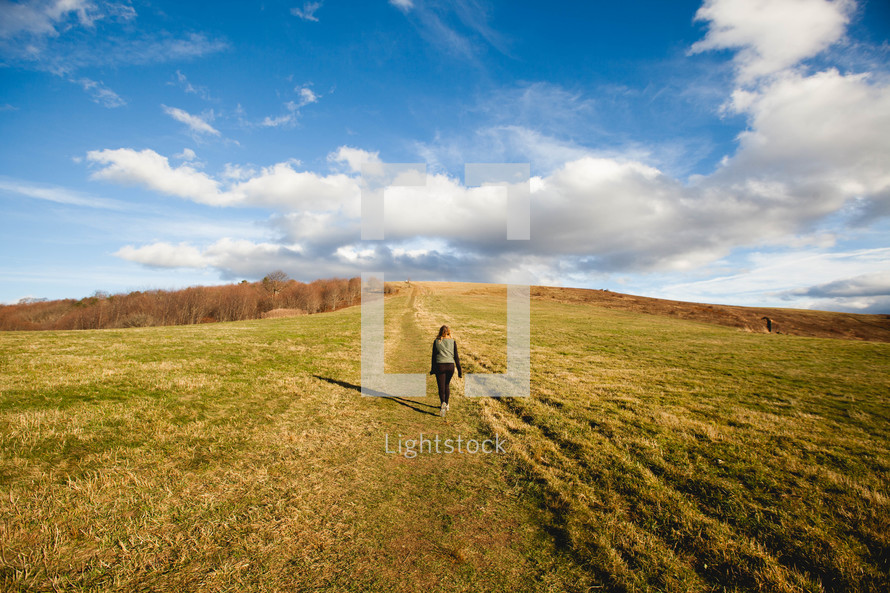 a woman walking through an empty field 