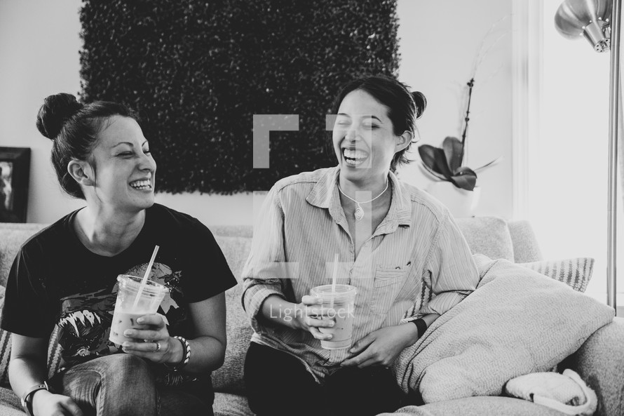 best friends sitting on a couch drinking iced coffees 