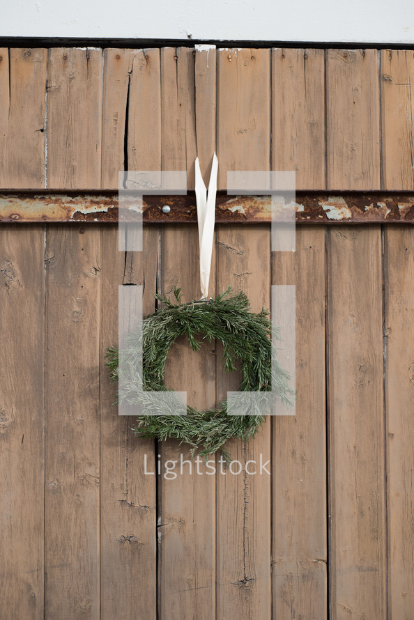 An evergreen wreath hanging on an old wooden gate.