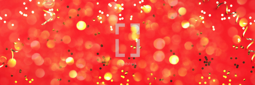 New year, Christmas background. Golden shiny glitter, sparkles, light bokeh on red background. Banner with copy space. Festive backdrop for greeting card