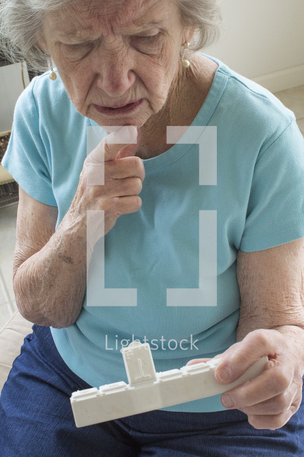 elderly woman looking at her pill box 