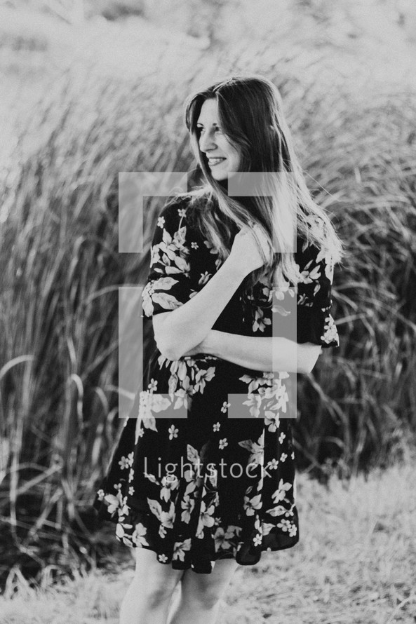 a woman in a floral dress standing in a field 