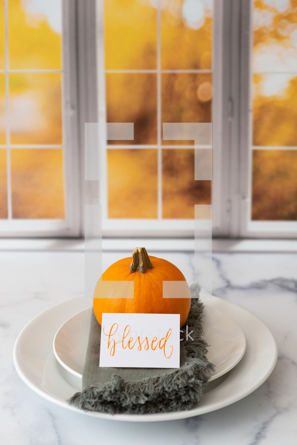 Thanksgiving place setting with the word blessed in front of a kitchen window