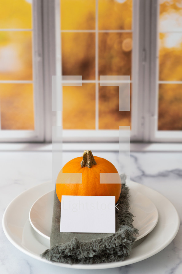 Thanksgiving place setting with a blank card in front of a kitchen window