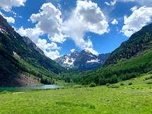 green meadow and lake in a glacial valley below Maroon Bells, Colorado Rocky Mountains