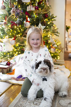 Little girl with dog in front of Christmas tree