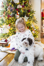 Little girl in front of Christmas tree with dog