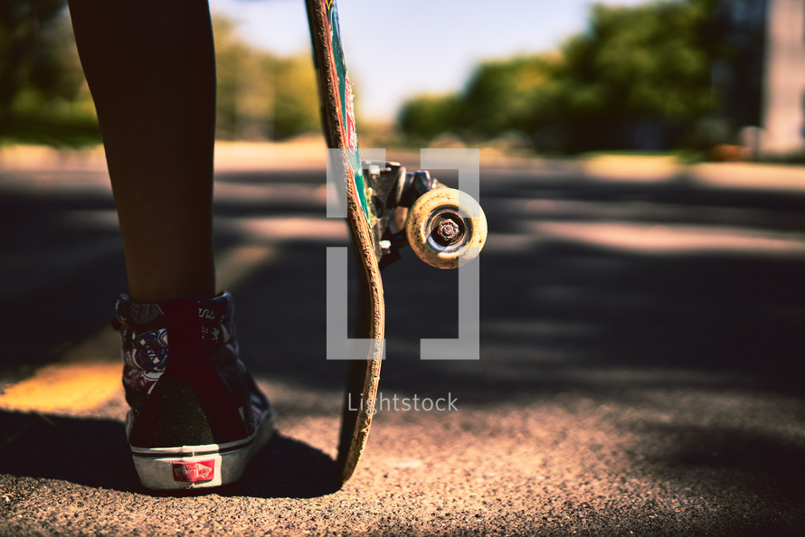 legs of a young man beside his skateboard 