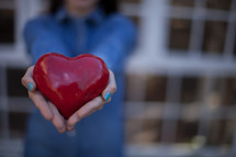 A woman's hands holding out a red heart